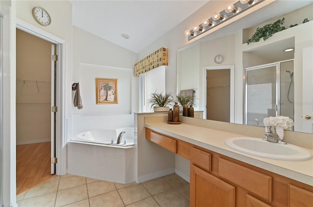 bathroom with tile patterned floors, a garden tub, a stall shower, a spacious closet, and vaulted ceiling