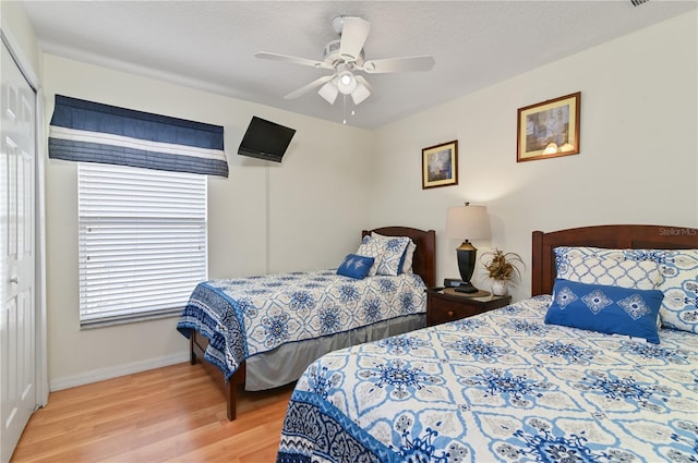 bedroom with a textured ceiling, wood finished floors, a closet, baseboards, and ceiling fan