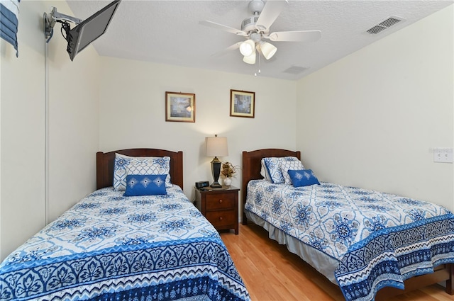 bedroom with visible vents, a textured ceiling, a ceiling fan, and wood finished floors