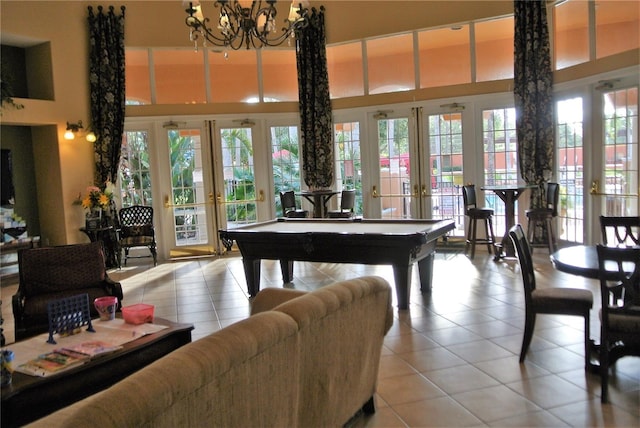 rec room featuring billiards, french doors, a towering ceiling, tile patterned floors, and a notable chandelier