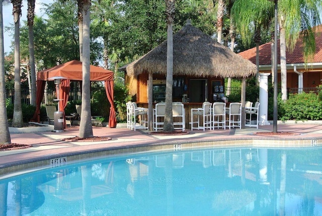 pool featuring a gazebo, outdoor dry bar, and a patio area