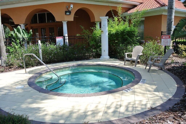 view of swimming pool featuring a patio, fence, and a hot tub