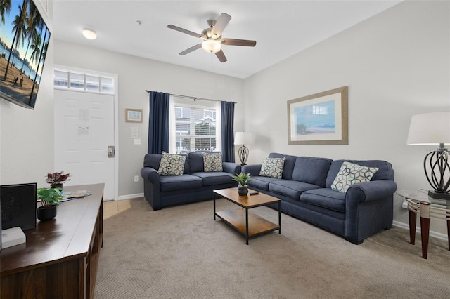 living area with baseboards, light carpet, and ceiling fan