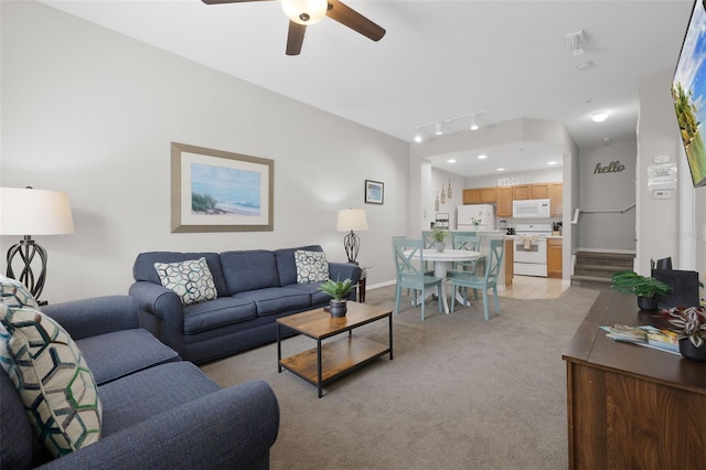 living area featuring stairway, baseboards, ceiling fan, track lighting, and light carpet