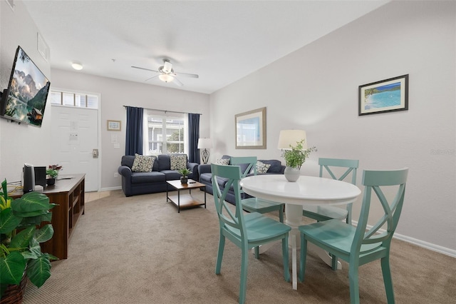 dining area featuring baseboards, light carpet, and a ceiling fan