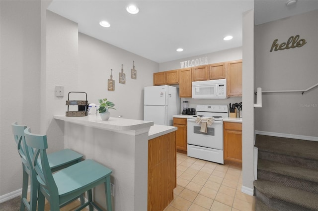 kitchen with a breakfast bar, white appliances, light tile patterned floors, and light countertops