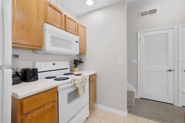 kitchen with visible vents, white appliances, light countertops, light tile patterned floors, and baseboards