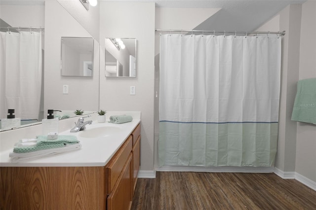 full bathroom featuring curtained shower, vanity, baseboards, and wood finished floors