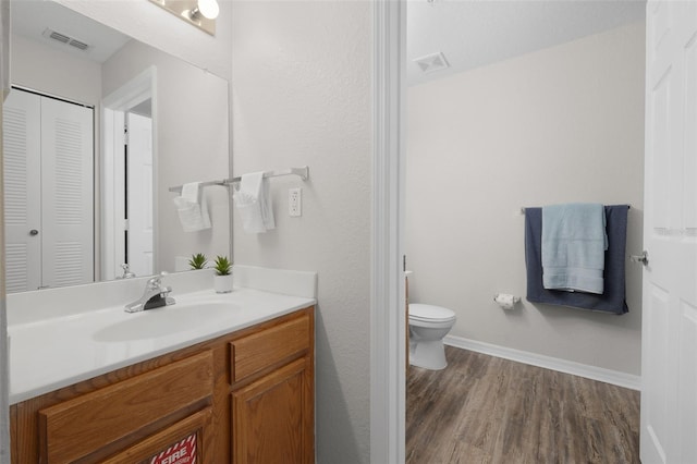 bathroom featuring visible vents, toilet, wood finished floors, and vanity