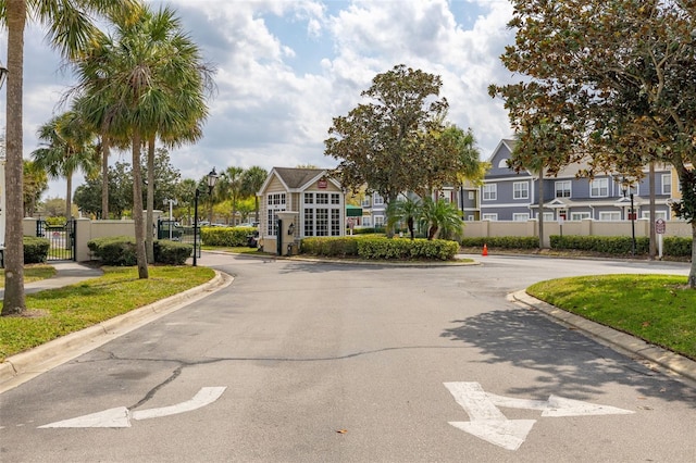 view of street with curbs, a gate, a gated entry, a residential view, and street lights