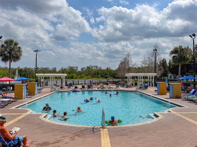 community pool with a pergola, a patio, and fence