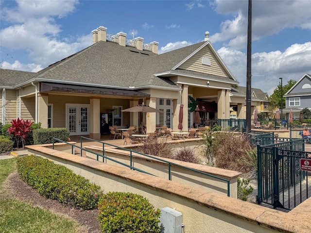 back of property featuring a patio, french doors, fence, and roof with shingles