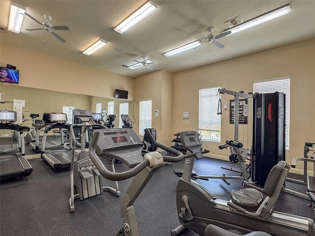 gym with ceiling fan, baseboards, visible vents, and a textured ceiling