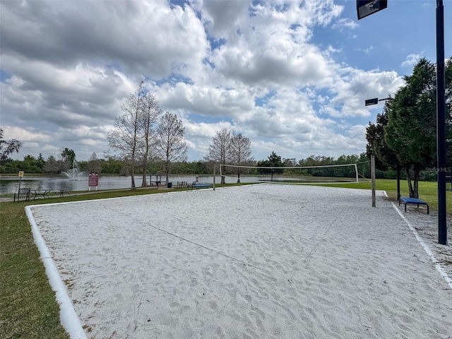 surrounding community with a lawn, volleyball court, and a water view