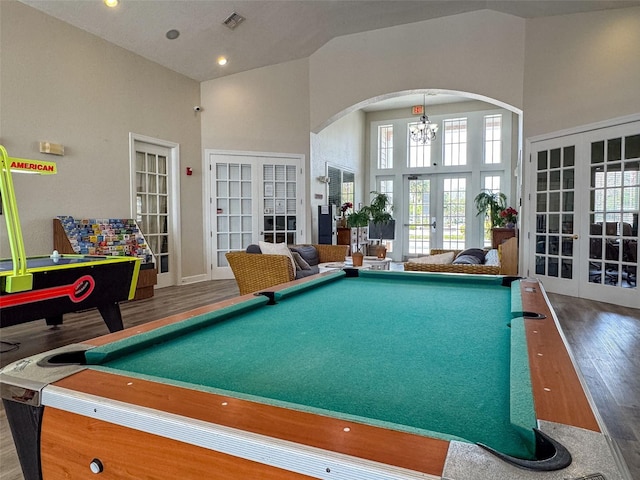 game room featuring wood finished floors, visible vents, high vaulted ceiling, arched walkways, and french doors