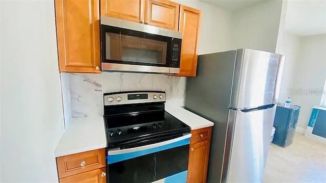 kitchen with decorative backsplash, brown cabinets, appliances with stainless steel finishes, and light countertops