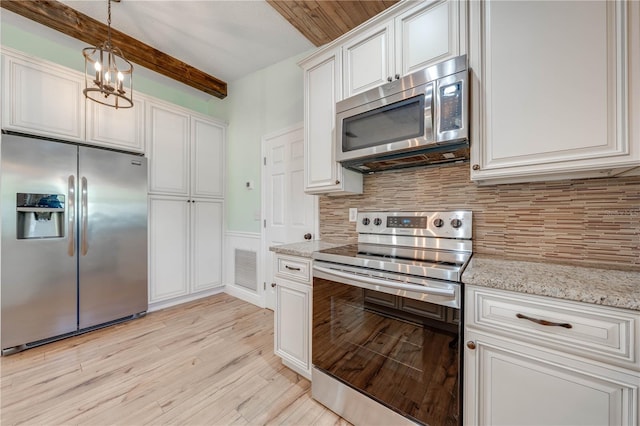 kitchen with white cabinets, light wood-style floors, appliances with stainless steel finishes, pendant lighting, and backsplash