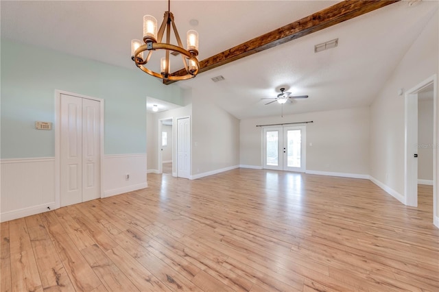 unfurnished room with visible vents, ceiling fan with notable chandelier, french doors, light wood-style floors, and wainscoting