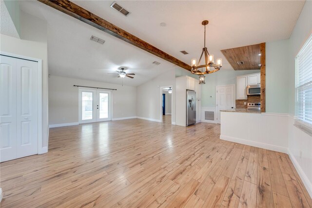 unfurnished living room featuring lofted ceiling with beams, light wood-style flooring, ceiling fan with notable chandelier, and visible vents