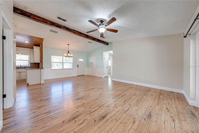 unfurnished living room featuring visible vents, lofted ceiling with beams, light wood-style flooring, ceiling fan with notable chandelier, and a textured ceiling