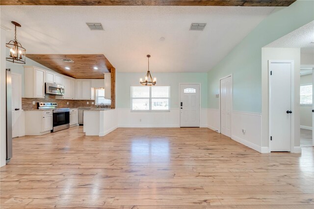 kitchen featuring visible vents, open floor plan, appliances with stainless steel finishes, white cabinets, and a chandelier