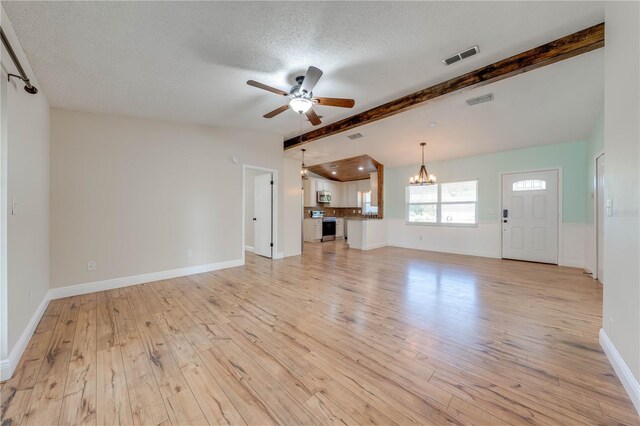 unfurnished living room with visible vents, light wood-style flooring, vaulted ceiling with beams, a textured ceiling, and ceiling fan with notable chandelier