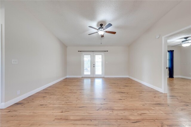 unfurnished room with light wood finished floors, french doors, a textured ceiling, and baseboards