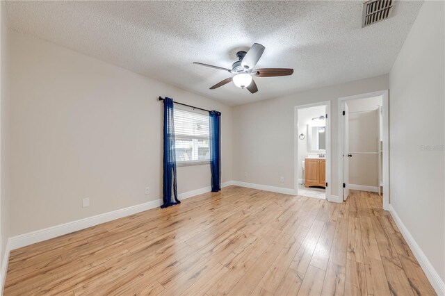 unfurnished bedroom with visible vents, light wood-style flooring, a textured ceiling, and baseboards