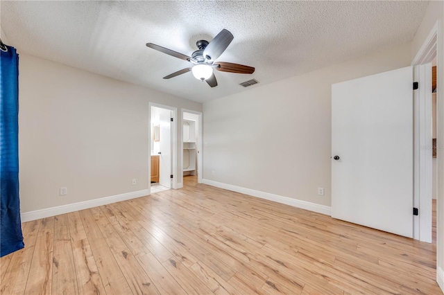 unfurnished bedroom featuring light wood-style flooring, baseboards, visible vents, and a textured ceiling