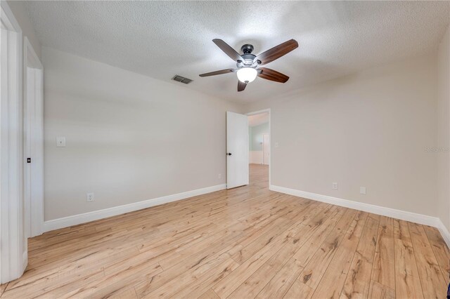 unfurnished room featuring visible vents, light wood-style flooring, a textured ceiling, baseboards, and ceiling fan