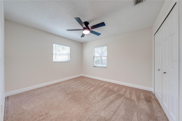 unfurnished bedroom with visible vents, baseboards, carpet floors, a closet, and a textured ceiling