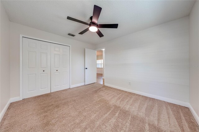 unfurnished bedroom featuring a closet, carpet floors, a textured ceiling, and visible vents