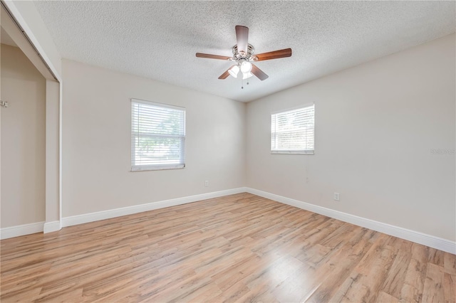 empty room with a wealth of natural light, baseboards, and light wood finished floors