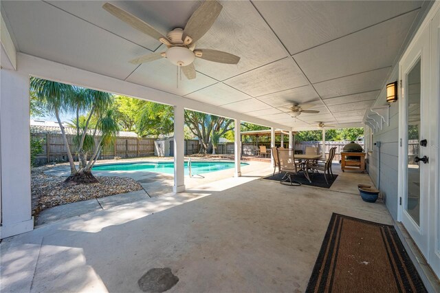 view of swimming pool featuring outdoor dining space, a patio, a fenced backyard, and a ceiling fan