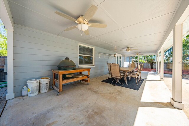 view of patio with ceiling fan, outdoor dining space, and fence