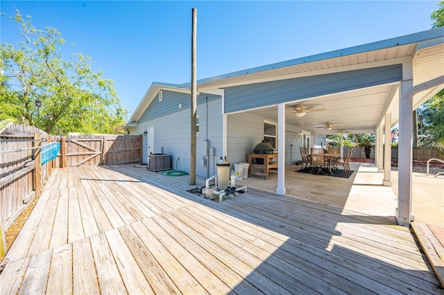 wooden deck featuring a gate, a ceiling fan, outdoor dining area, a fenced backyard, and central AC