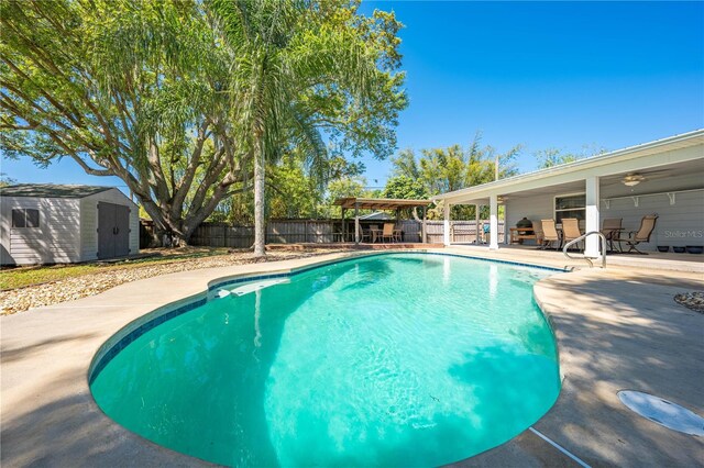 view of swimming pool with a fenced in pool, a storage shed, a fenced backyard, an outbuilding, and a patio