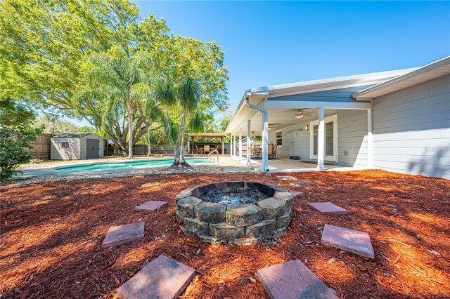 view of yard with a storage unit, a patio, a fenced backyard, an outdoor structure, and ceiling fan