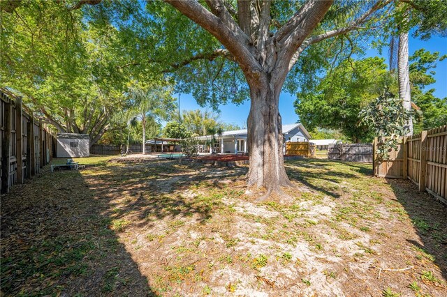 view of yard featuring a storage unit, an outbuilding, and a fenced backyard