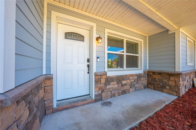 entrance to property featuring covered porch and stone siding