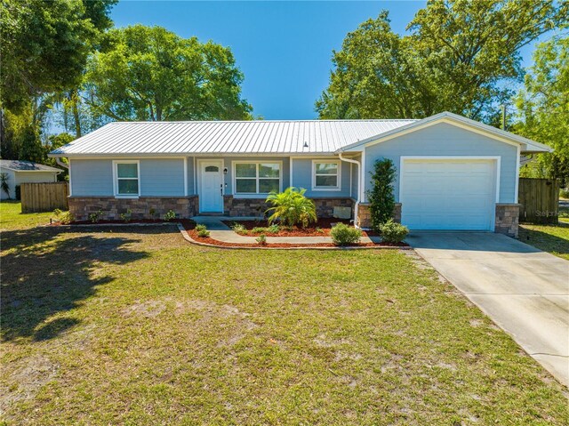 single story home with a garage, stone siding, a front yard, and fence