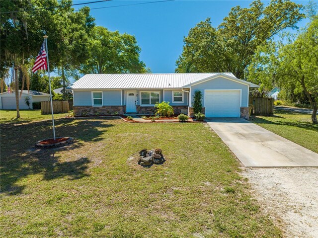 ranch-style home featuring stone siding, an attached garage, metal roof, and fence