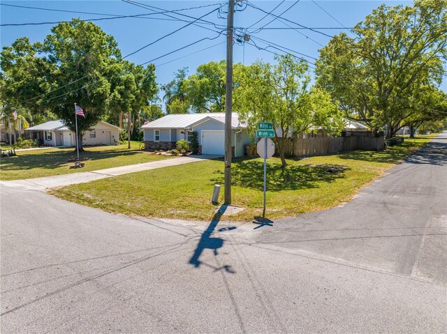 view of front of home featuring a garage, concrete driveway, a front lawn, and fence