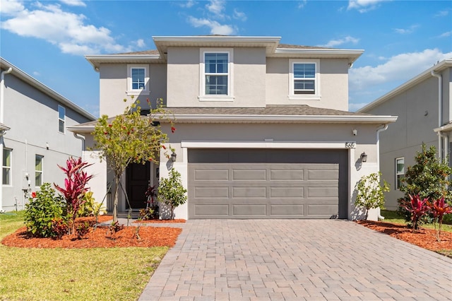 traditional home featuring stucco siding, a front lawn, decorative driveway, and a garage