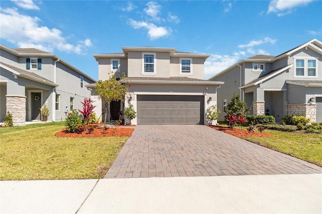 prairie-style house with a front yard, decorative driveway, a garage, and stucco siding