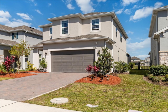 view of front facade with stucco siding, decorative driveway, fence, a front yard, and a garage