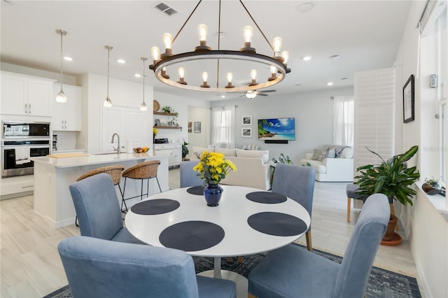 dining area with recessed lighting, visible vents, a raised ceiling, and light wood-style floors