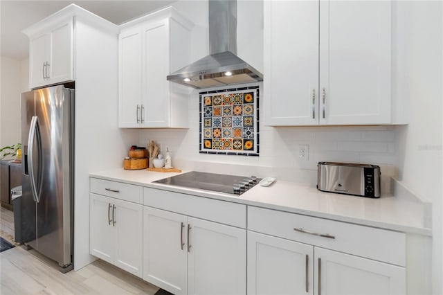 kitchen with backsplash, white cabinetry, wall chimney exhaust hood, stainless steel fridge with ice dispenser, and black electric cooktop