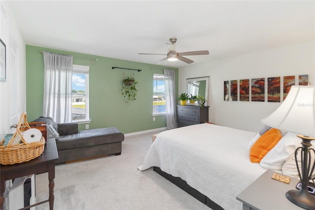 carpeted bedroom featuring baseboards, multiple windows, and a ceiling fan