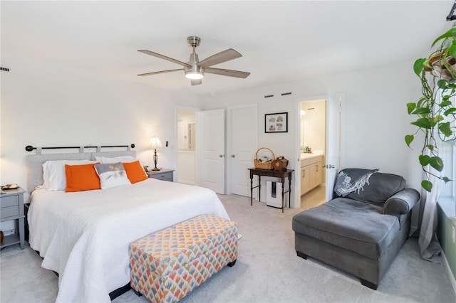 bedroom featuring connected bathroom, light carpet, and ceiling fan